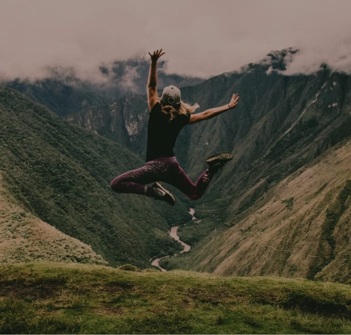 Frau, die in den Bergen in die Luft springt